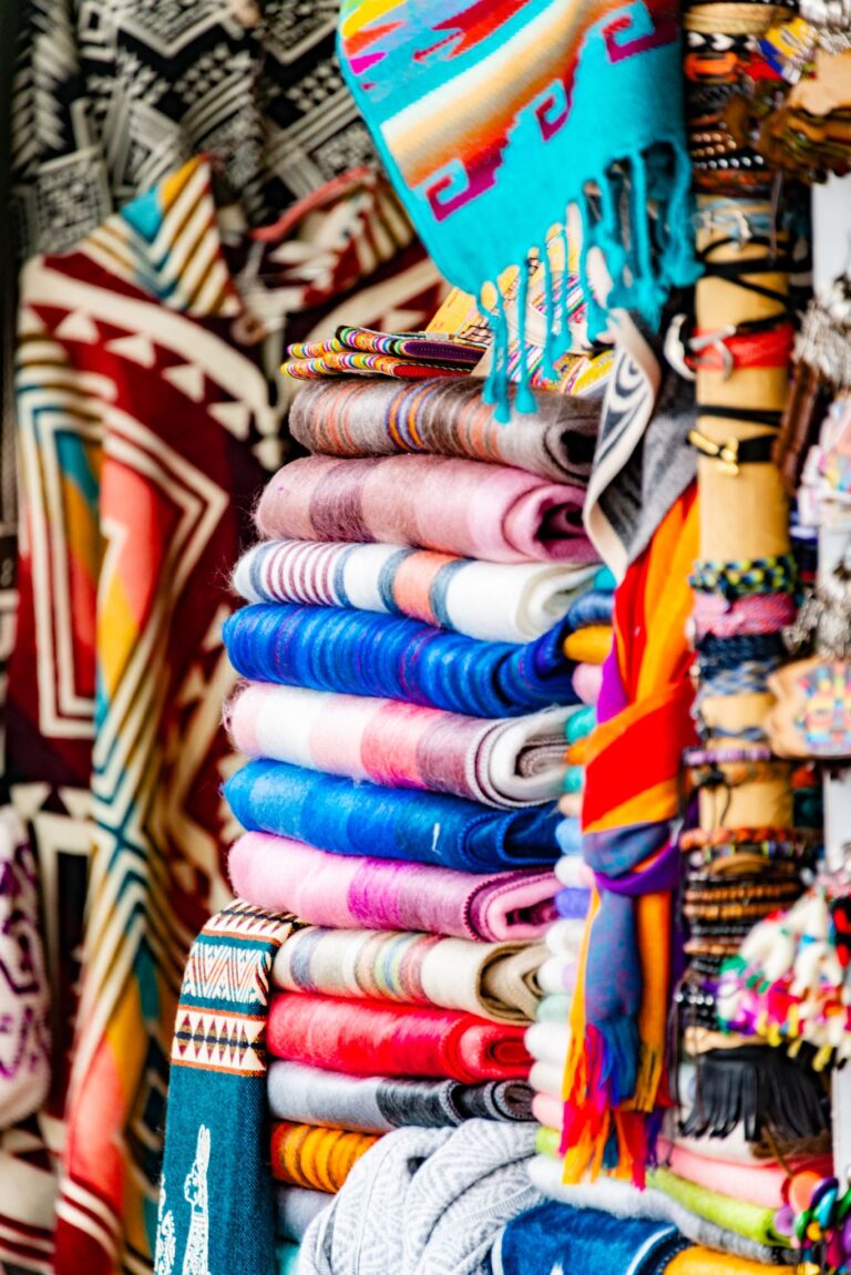 Vibrant stack of handmade embroidered textiles at a market stall, rich in patterns and colors.